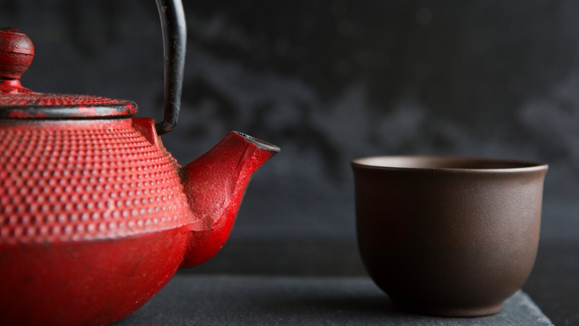 Rote gusseiserne Teekanne mit Teeschale Red iron tea pot with tea bowl