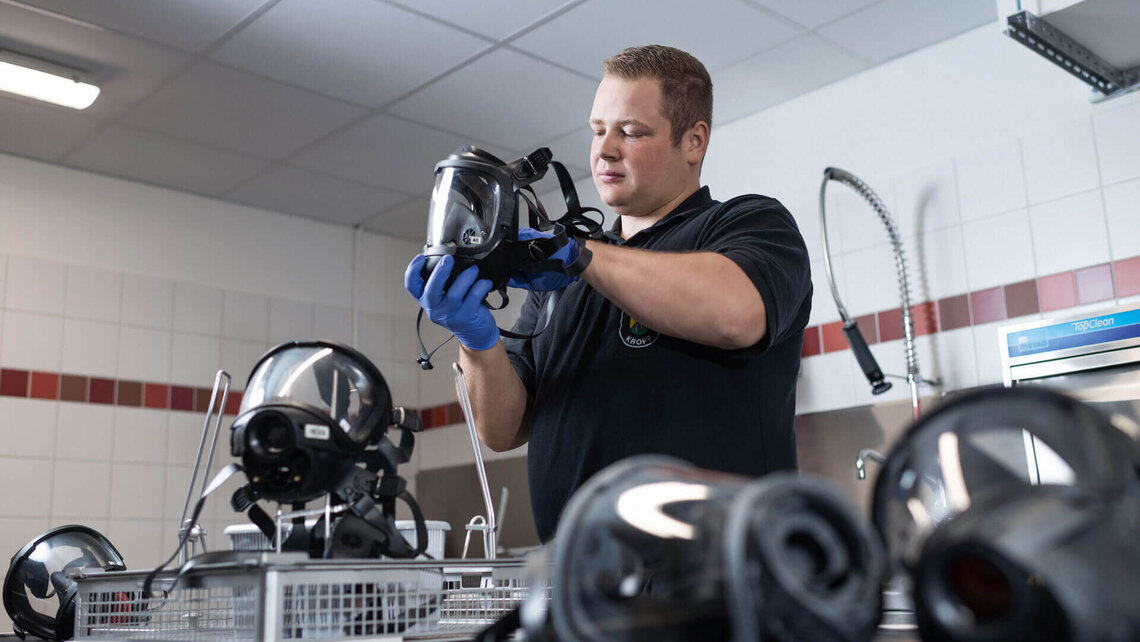 Atemschutzgerätewart bestückt Korb mit Atemschutzmasken zur Reinigung im TopClean M von Meiko Atemschutzgerätewart bestückt Korb mit Atemschutzmasken zur Reinigung im TopClean M von Meiko