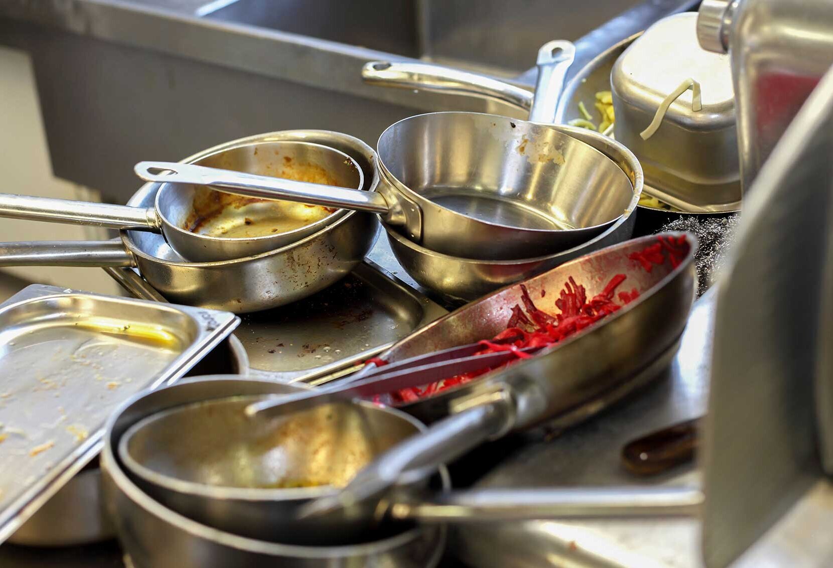 Dirty pots and pans are piled up in the kitchen's sink Dirty pots and pans are piled up in the kitchen's sink