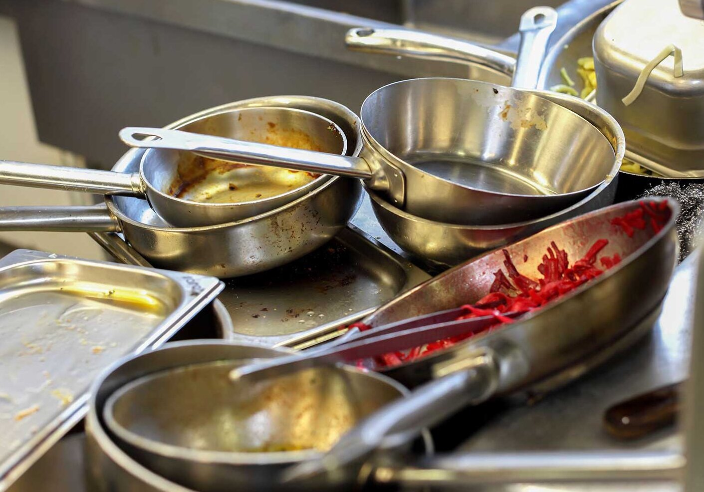 Dirty pots and pans are piled up in the kitchen's sink Dirty pots and pans are piled up in the kitchen's sink