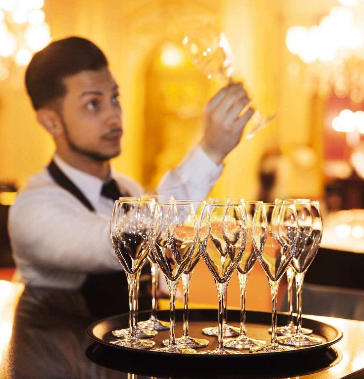 Waiter checks champagne glass for cleanliness and glass corrosion Waiter checks champagne glass
