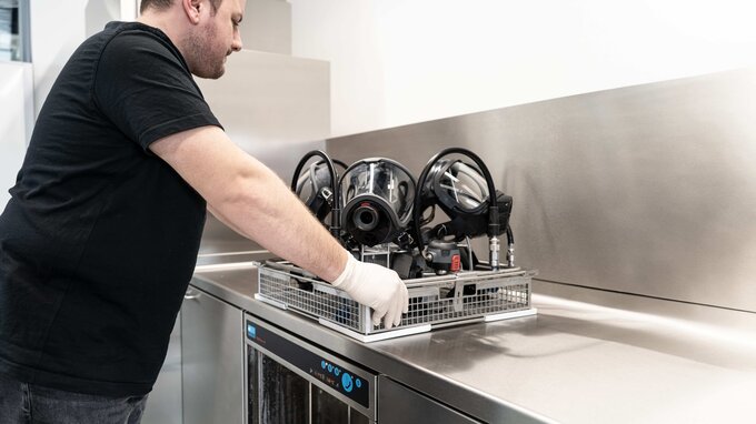 Atemschutzgerätewart setzt vorgereinigte PSA in das TopClean M ein Atemschutzgerätewart setzt vorgereinigte PSA in das TopClean M ein